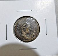 Front side of the ancient Roman coin showing a profile bust, worn with indistinct details.