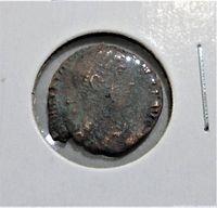 Front side of the ancient Roman coin showing a worn portrait of a figure in profile with partial inscription.