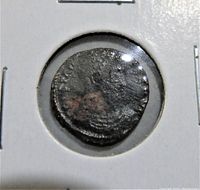 Obverse side of the ancient Roman coin showing a worn profile bust and partial inscriptions.