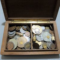 Open handcrafted wooden box divided into two compartments filled with various world coins and small vials containing gold flakes