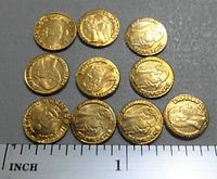 10 mini gold plated coins featuring Maximillion's profile and a buffalo, shown against a ruler for size reference under 1 inch in diameter.