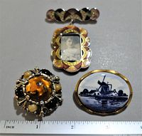 Top-down view of four pins near ruler for size reference, showing details of enamel, photo, and painted porcelain.