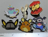 Front view of all five Pokemon collectible pins displaying teapot, rabbit, fox, mouse, and humanoid designs with colorful enamel finishes and detailed artwork.