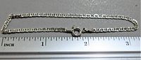 Full view of sterling silver chain link bracelet laid next to ruler showing length just over 3 inches.