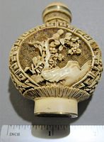 Front side of the snuff bottle showing carved floral branch and natural patterns with measurement for size reference