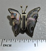 Front view of vintage sterling silver butterfly brooch featuring abalone shell wings, placed against ruler showing approximately 1 inch size.