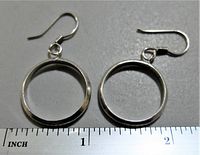 Pair of vintage sterling silver hoop earrings laid flat on a grey surface with ruler showing size around 1.25 inches.