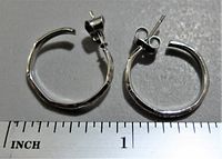 Top-down photo of both sterling silver hoop earrings placed on a surface with a ruler beneath showing size about 1 inch diameter.