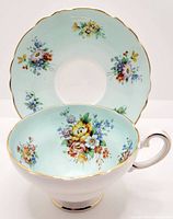 Photo of tea cup and saucer showing floral design, gold trim, and scale.
