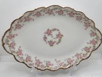 Full view of oval Limoges serving platter with pink floral wreath center and floral border, scalloped edge with gold trim.