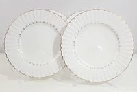 Two vintage J & G Meakin dinner plates shown side by side, showcasing the fluted edges with gold trim and the black Fleur de Lis decorative pattern around the center.