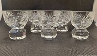 Front view of 5 footed pinwheel crystal shot glasses showing etched detailed pinwheel/starburst pattern on the bowl with thick crystal footed base.