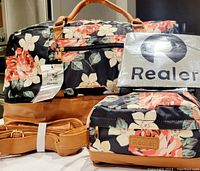 Photo showing both weekender and toiletry bags with floral pattern and brown leather straps, Realer tags visible, along with dust cover and reusable shopping bag.