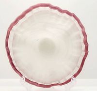 Top down view of the white opalescent glass bowl showing the burgundy ruffled edge and scalloped texture.