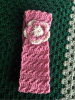Front view of the handcrafted crocheted headband in pink and white with flower decoration.