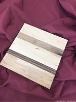 Top view of square wooden board showing natural wood grain with light and dark wood strips