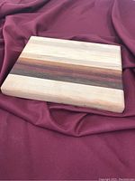 Front view of handcrafted wooden cutting board showing wood grain and color stripes.