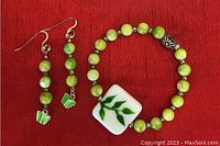 Photo of handcrafted matching bracelet and earrings set featuring green beads, silver spacers, green butterfly charms, and a leaf design bead on bracelet.