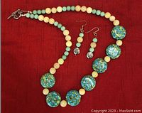 Photo of handcrafted necklace and matching earrings on red background showing bead colors and necklace length