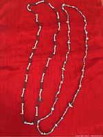 Two beaded necklaces laid on a red background, showcasing overall length and bead arrangement