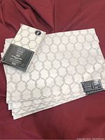 Set of silvery grey placemats folded with matching napkins still wrapped in packaging.