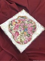 Floral three-sectioned serving dish with gold-toned handle displayed on satin fabric inside box