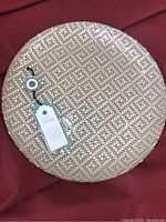 Full view of round woven serving plate with natural woven pattern and product tag showing
