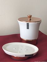 Photo of the Harman brand white ceramic container with rose gold lid and base paired with the soap dish, both brand new with stickers still on.