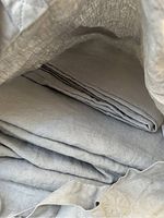 Folded grey linen bedding inside a tote bag.