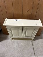 Back/side angle view of antique white medicine cabinet showing top and sides.
