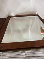 Photo of one 30-inch wood framed mirror with crown molding, showing dark wood frame and protective packing.