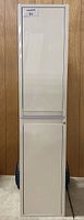 Front view of closed white linen cabinet showing upper and lower doors with plain panel design and clean white finish.