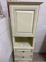 Full view of linen tower showing top cabinet door, open middle shelf, two drawers, and bottom cabinet door