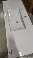 White ceramic sink top showing overall length and integrated basin shape with faucet hole