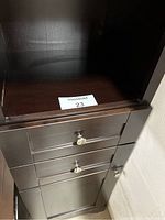 Close-up of open middle cubby and two drawers with metal knobs below.