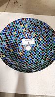 Top down view of the vessel sink showing the colorful checkered mosaic pattern inside with a central drain hole.
