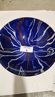 Top view of round blue glass vessel sink with white and copper veins.