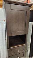 Full view of the tall linen cabinet showing the closed top door with espresso bamboo finish, open shelf below, and clean lines.