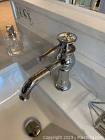 Installed faucet on sink with chrome finish and crystal-like handle knob.