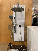 Assembled shower system mounted on display panel showing overhead and handheld shower heads, mixer bar and hose