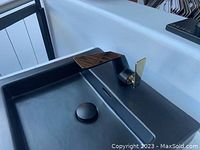 Installed view of black and gold single hole bathroom faucet mounted on black vanity top with integrated basin.