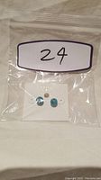 Turquoise stud earrings attached to white Fossil card, photo shows earrings in resealable plastic bag with label '24'.