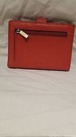 Photo of the orange leather wallet showing the back with a zipper pocket and Fossil branded zipper pull.