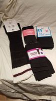 Photo showing black knit leg warmers with white and maroon stripes alongside black leggings and tights on white background.