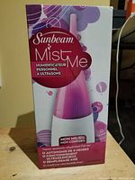 Box of Sunbeam MistMe ultrasonic humidifier showing product image and branding in pink and white.