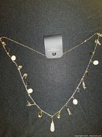 Full view of the necklace laid flat showing distribution of pendants including rose quartz, crystal drops, and small gold-tone charms on gold-tone chain.