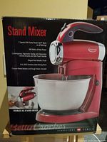 Packaging box showing red stand mixer with specifications including 7 speed settings, Turbo Power-Up Burst, 300 watt peak power, 3.0L stainless steel bowl, chrome-plated beaters and dough hooks included.