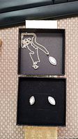 Photo showing sterling silver necklace with pendant and matching earrings in black box.