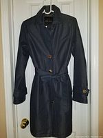 Front view of navy blue ladies trench coat with gold buttons and belt