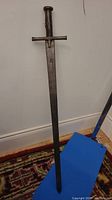 Full‐length view of sword upright against wall over blue pad